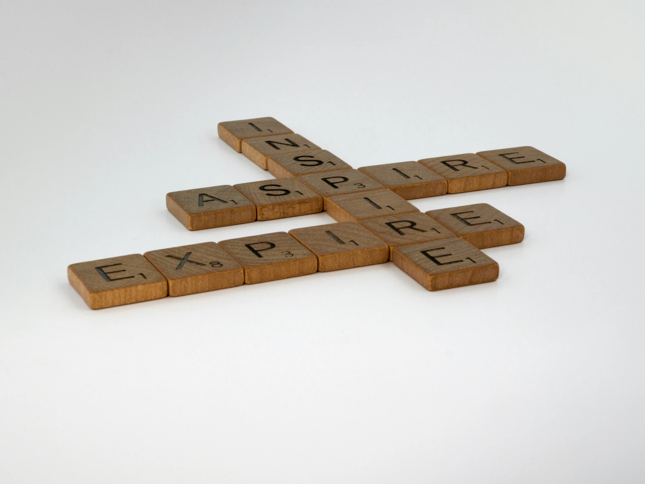 the words inspire and inspire made with scrabble tiles