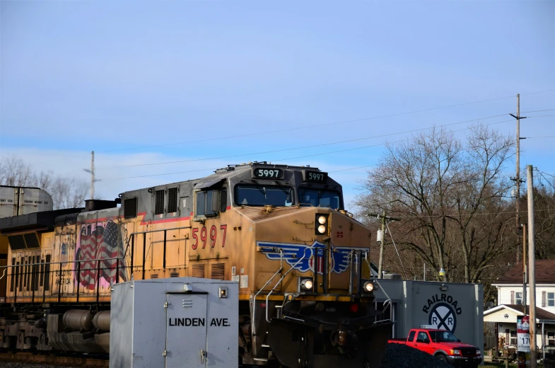 yellow train sitting next to houses and power lines