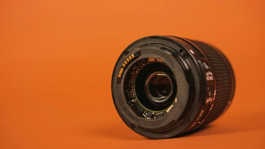 an old camera lens resting on top of an orange background