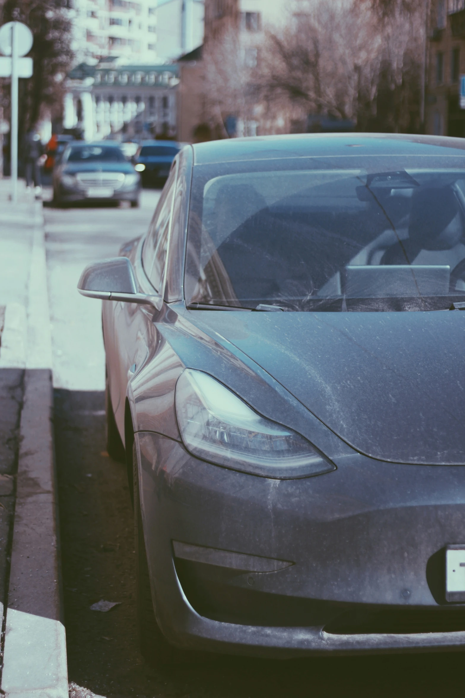 a dark colored electric car parked along a curb