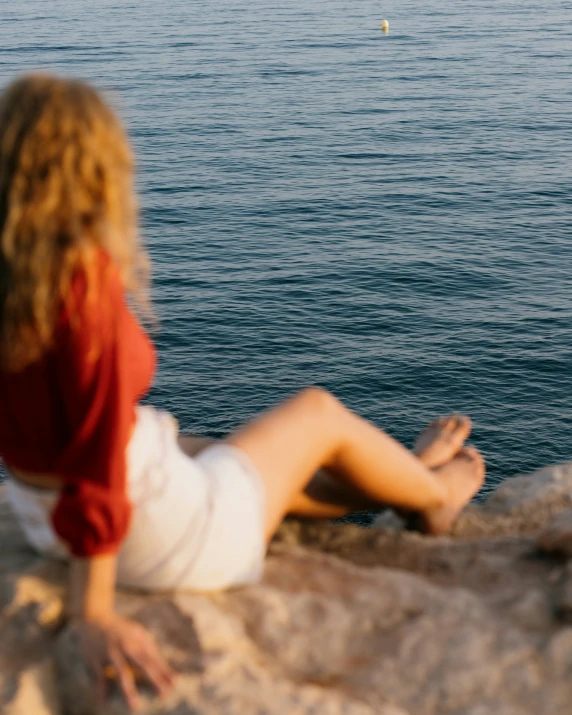 a woman sitting by a body of water