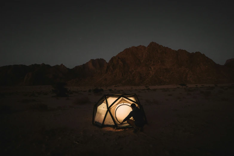 a person sitting inside of a tent on top of dirt