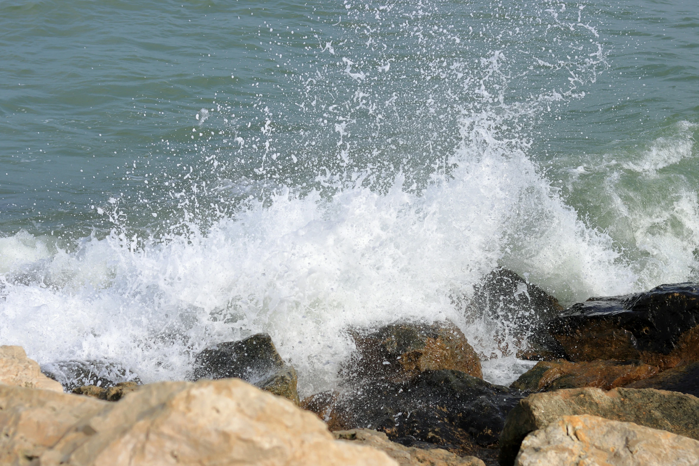 there is a large wave crashing on a rock