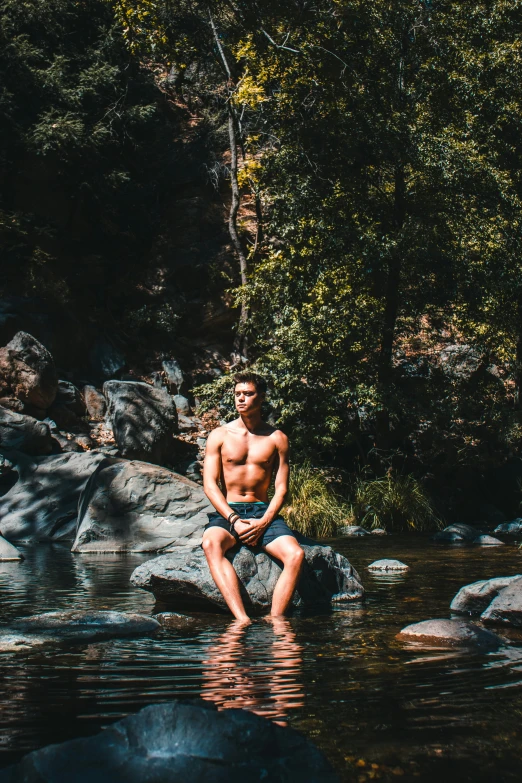 a man sitting on top of a rock near the water