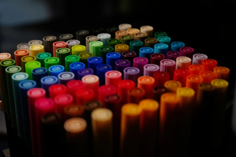 several multicolored pens are arranged in rows
