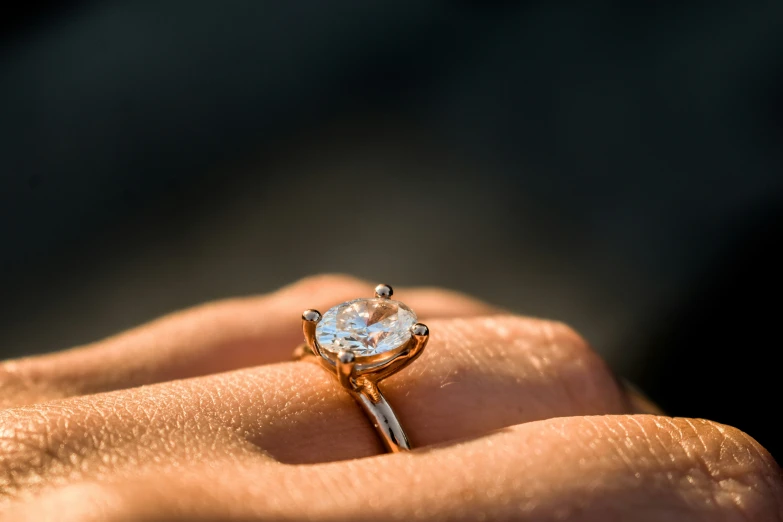 a white topaz and diamond ring on someone's hand