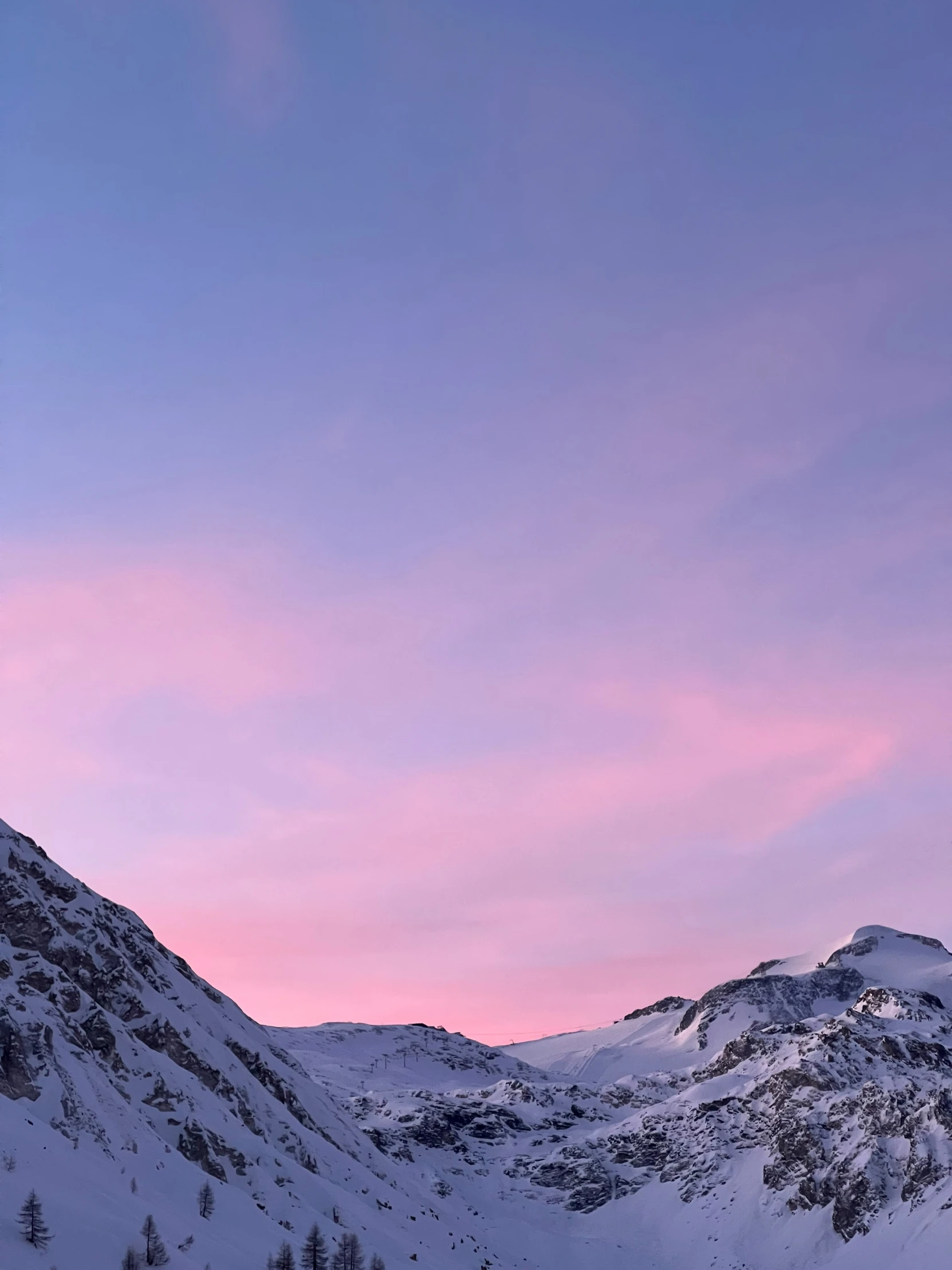 some snow covered mountains and one tree under the pink sky