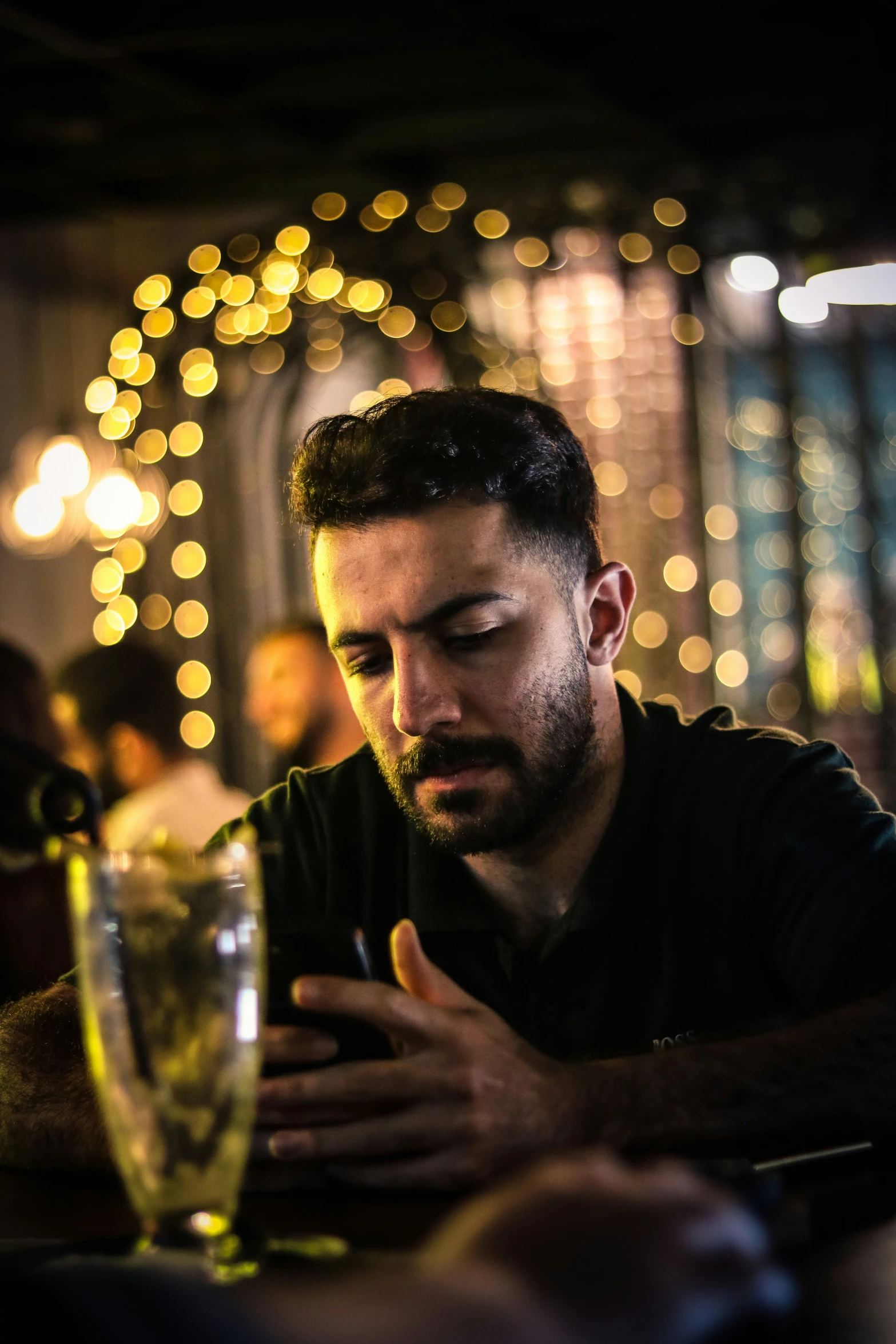 man in black shirt using smart phone while sitting at table