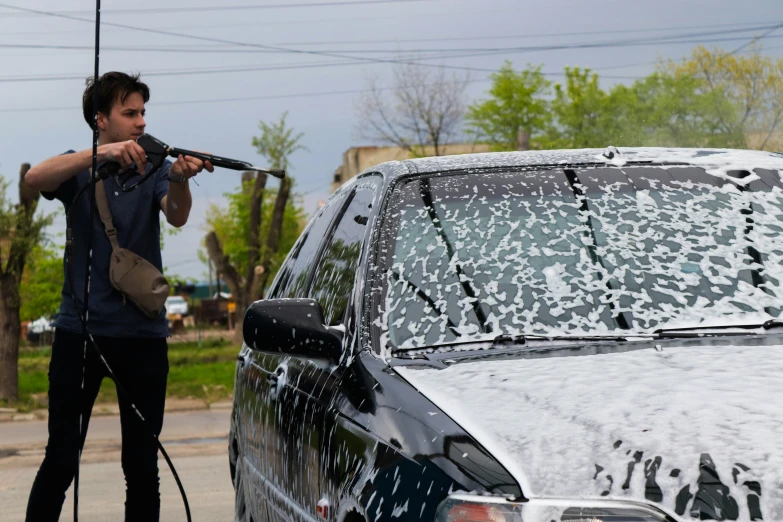 a person using a spray gun on the windshield of a car