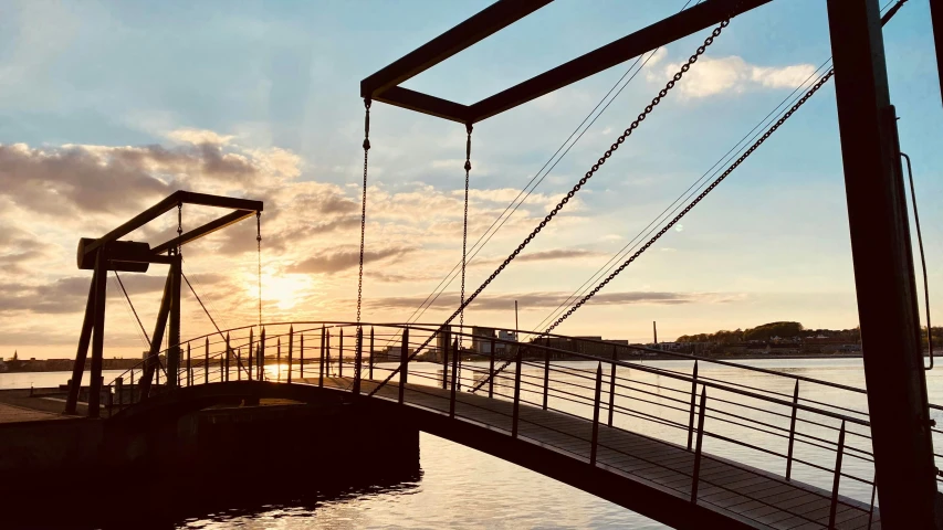 the sun is setting on the water at a dock