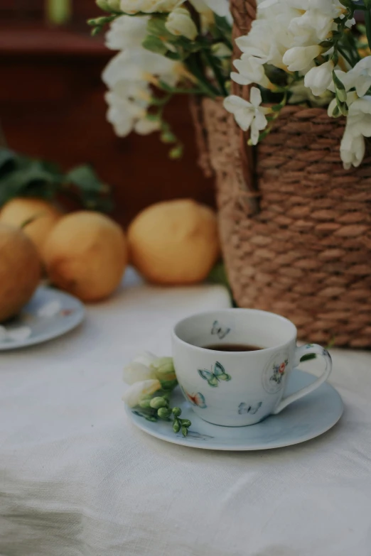 a tea cup and saucer are on a tablecloth with flowers