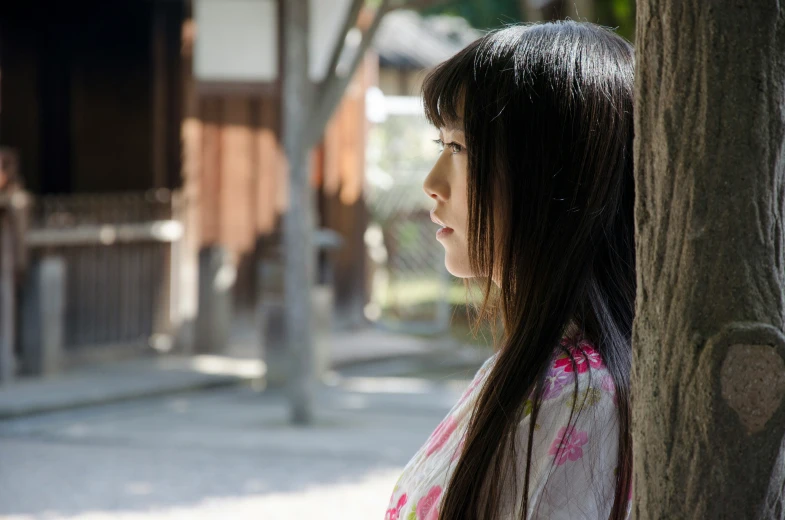 a young asian woman is looking out of a tree