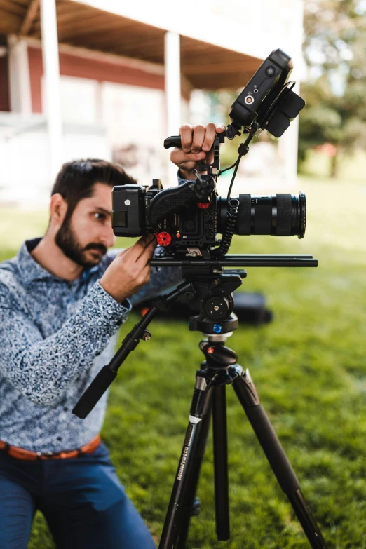 the man is sitting in the grass next to a camera