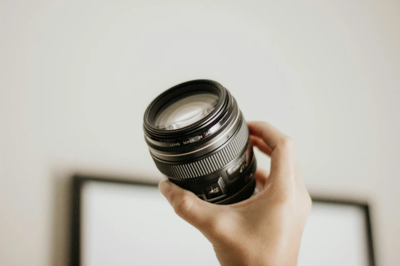 a hand holding an old - fashioned camera lens to the viewer