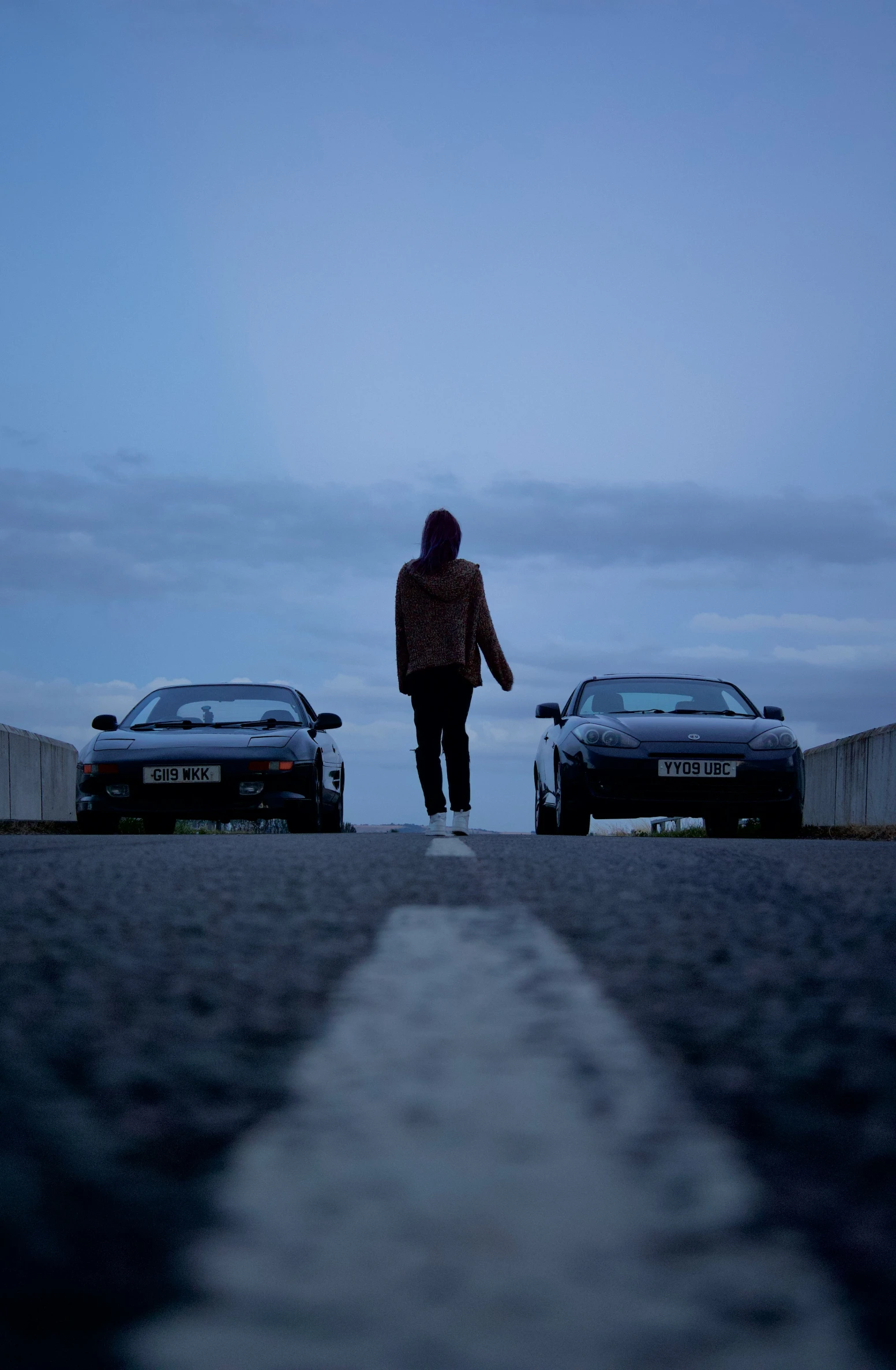 a person standing in the middle of road with cars