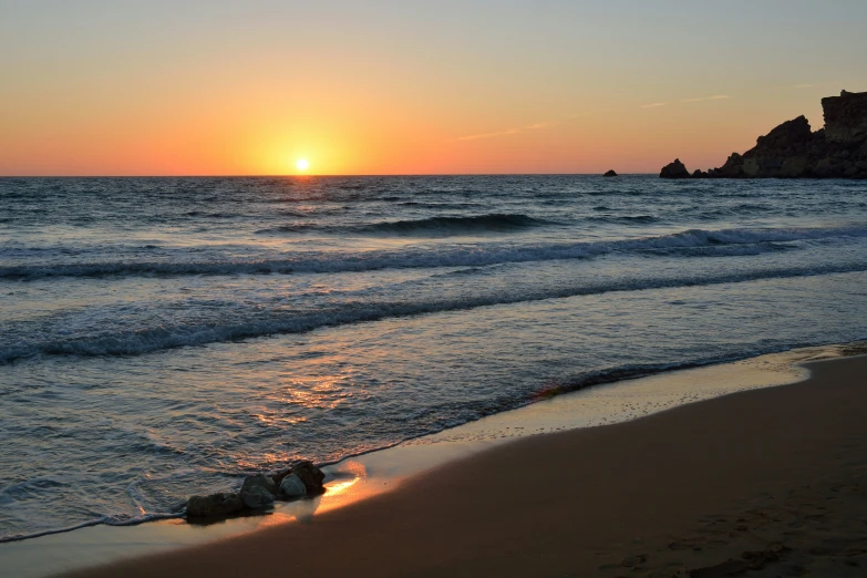 the sun is setting behind the rocky coastline