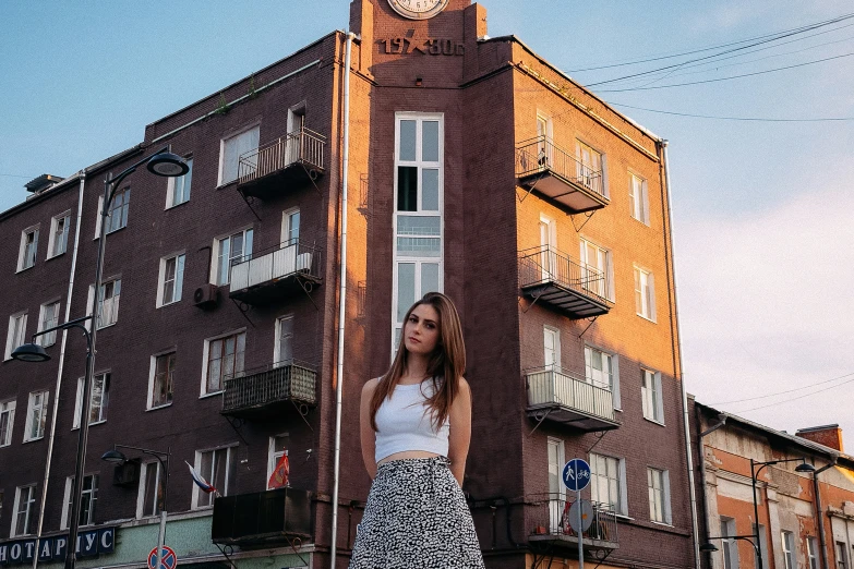 a young woman stands against a building in front of a tall clock tower