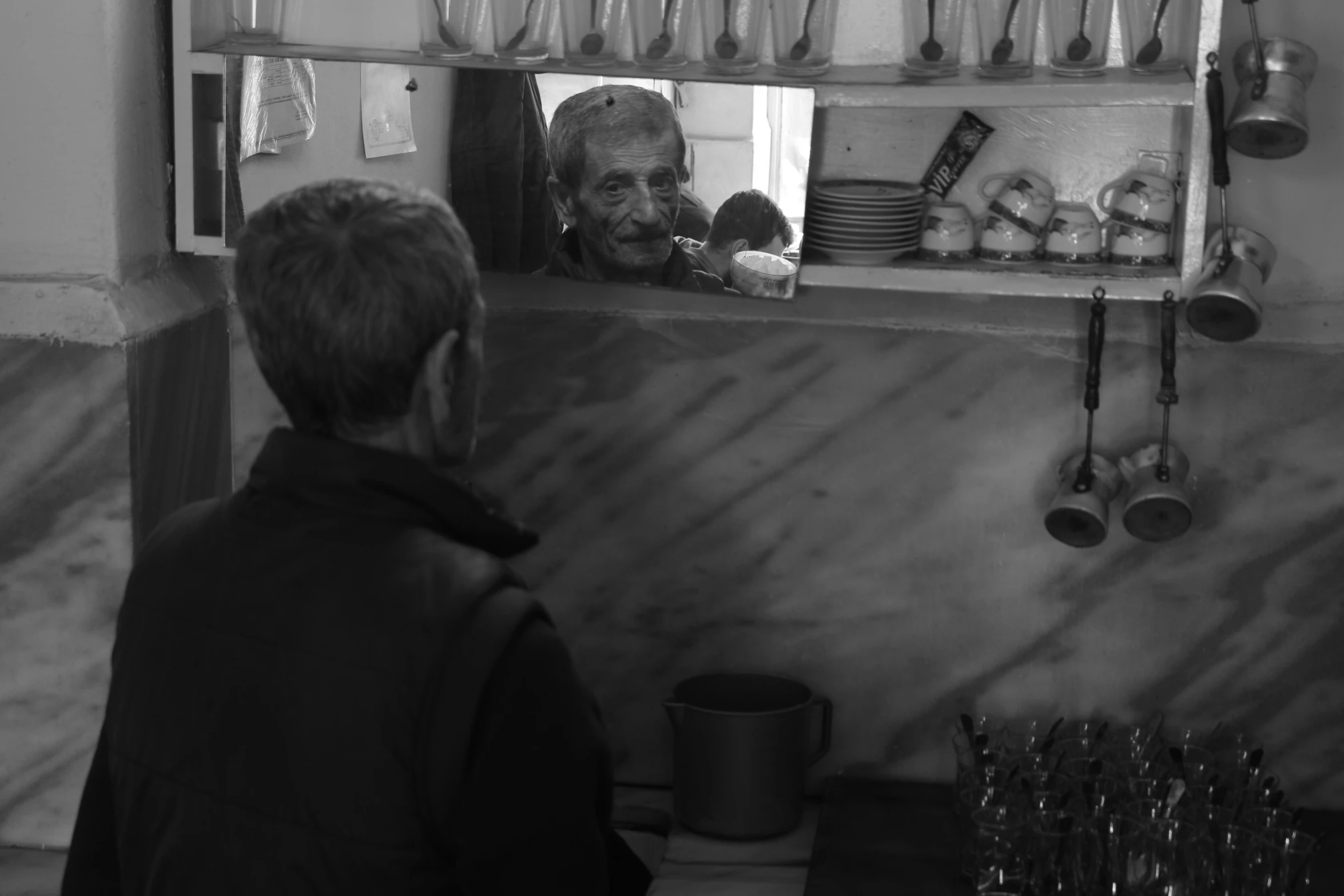 an older woman in a kitchen looking at her reflection in the mirror