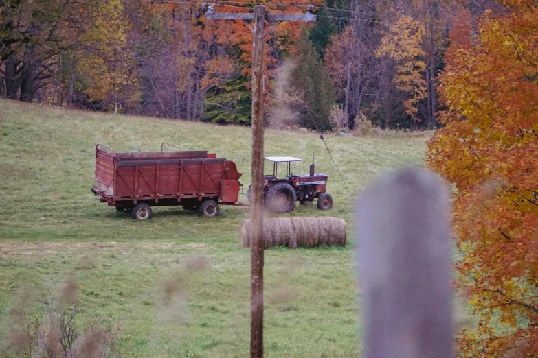 the tractor is driving near the hay bales in the pasture