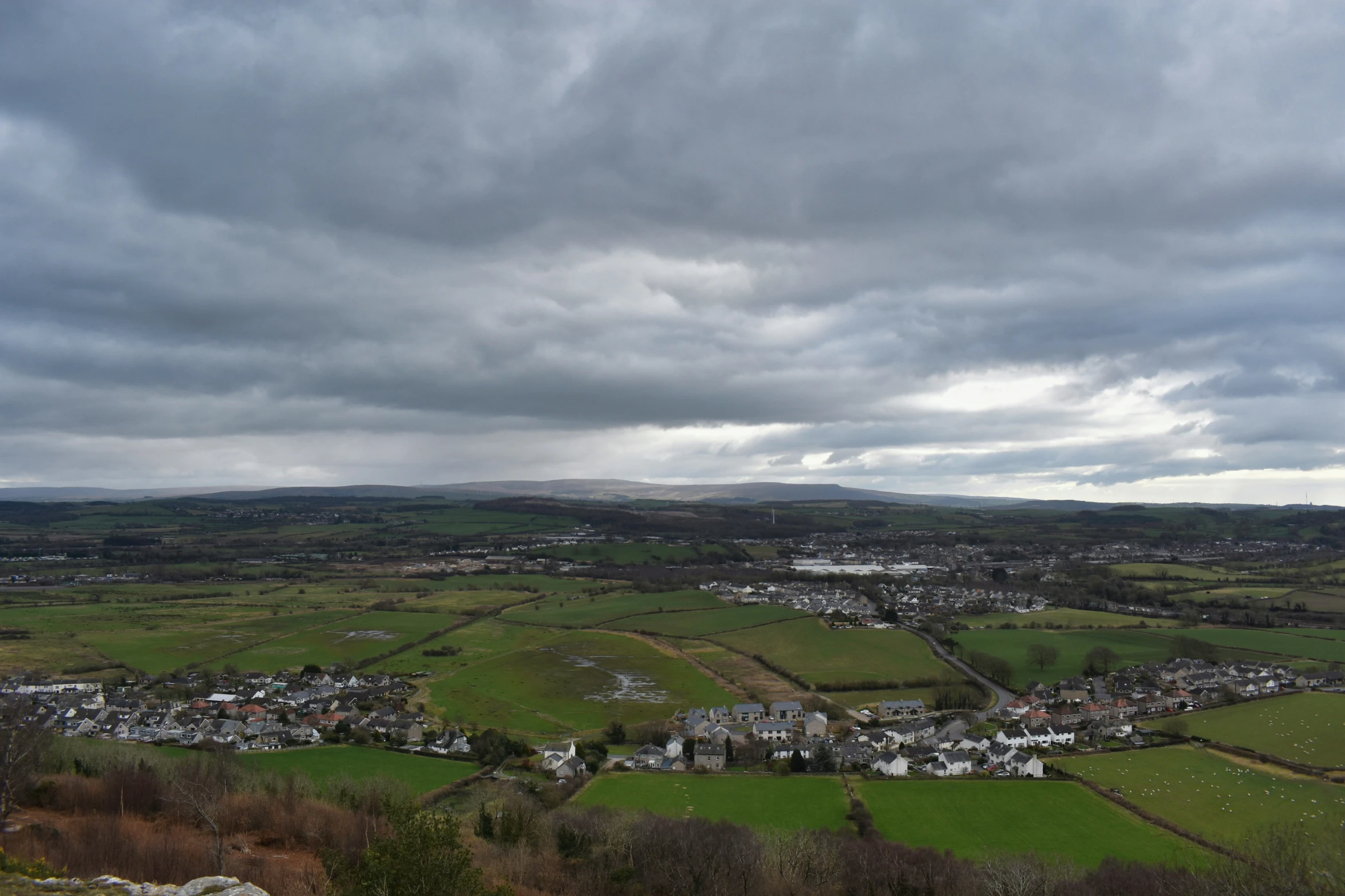 a cloudy day over a green countryside with white houses and farms