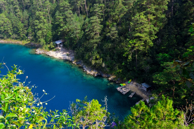 a small house on a hill above a lake in the middle of forest