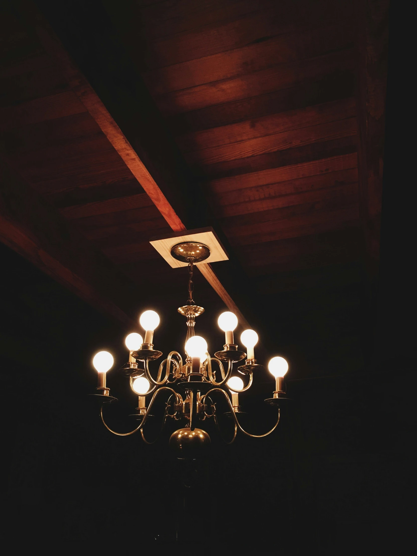 a chandelier hanging from a dark ceiling, with a square light on top