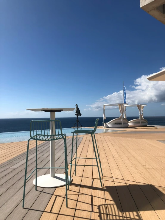 a pier with two white benches and two blue umbrellas