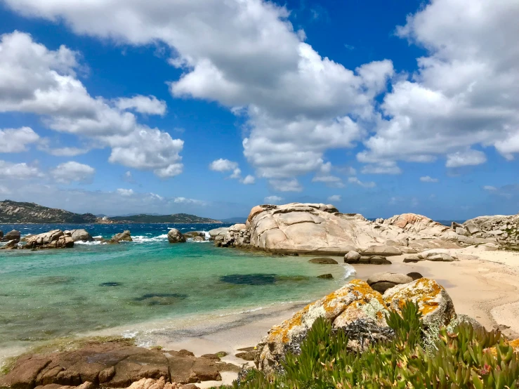 a rocky beach in front of some clear blue waters