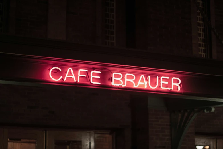 red neon sign saying cafe uer hangs outside of a restaurant