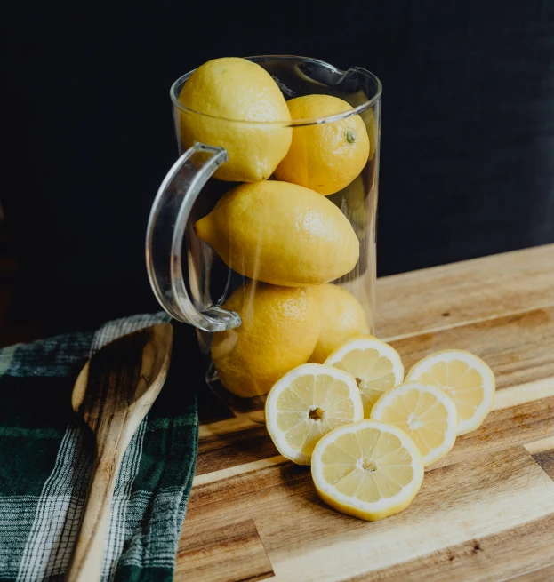 several lemons are on a  board with a glass mug