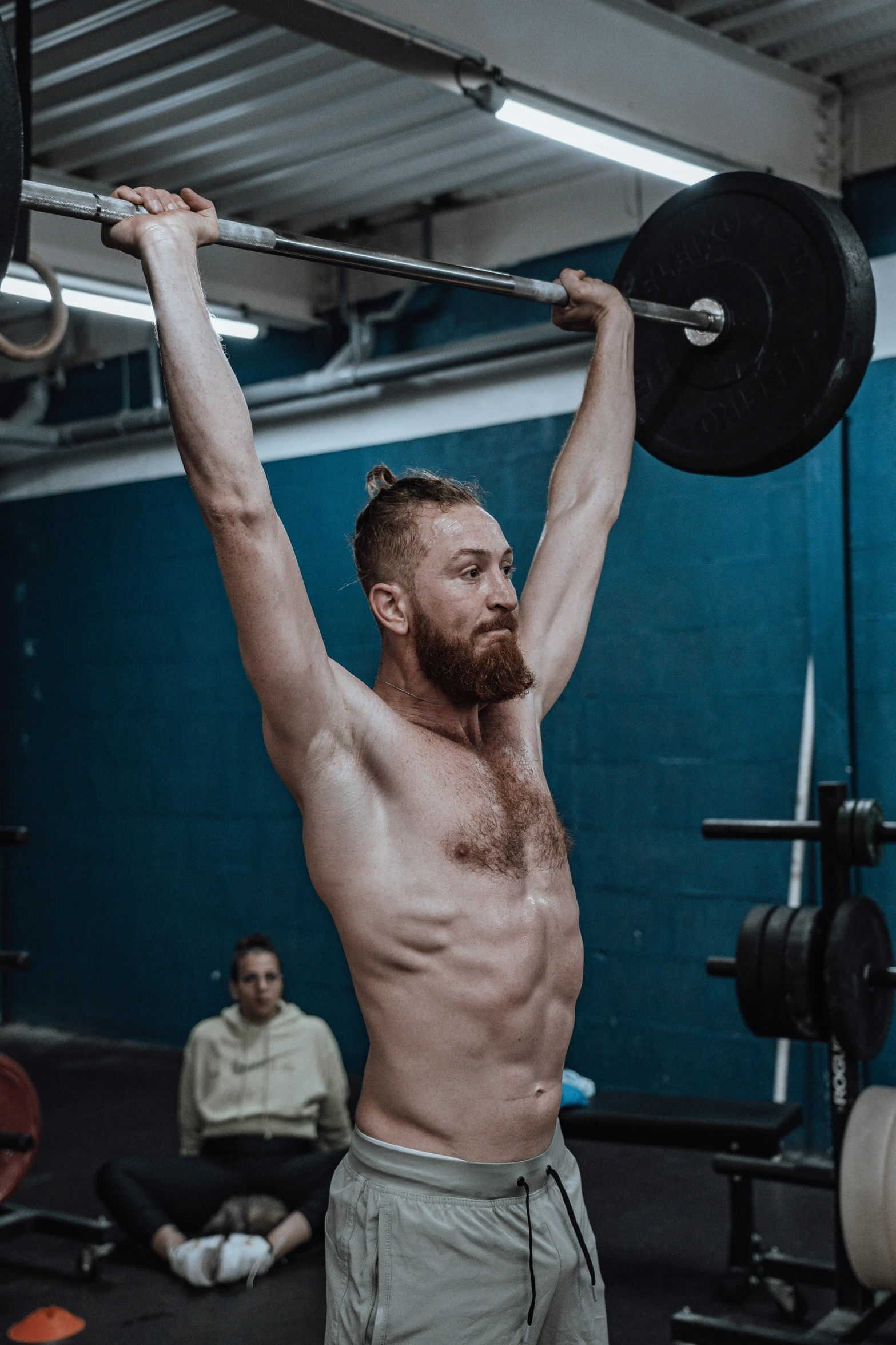 the man with the shirt off is doing a barbell pull