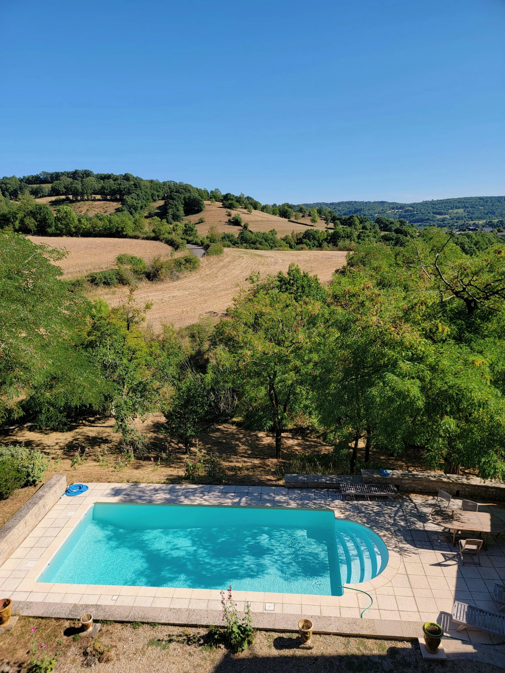 a swimming pool with no cover in the shade of trees