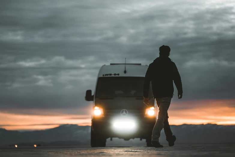 a person walking by a vehicle in the dark