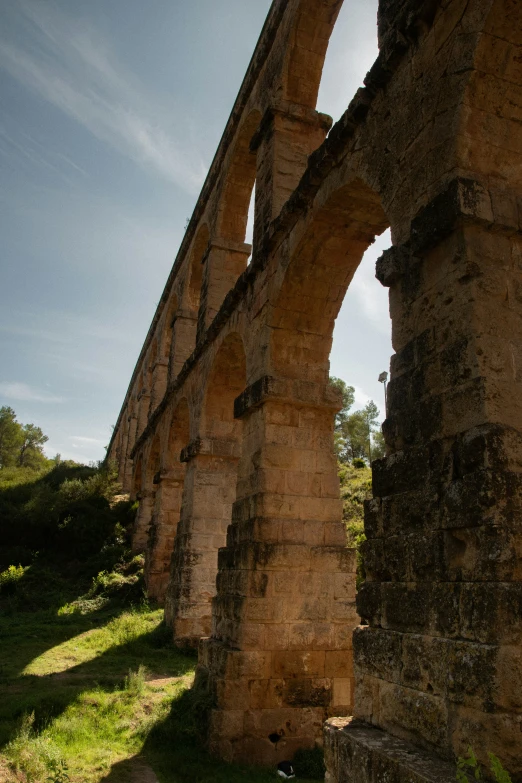 a stone bridge with arches on it sitting on a hillside