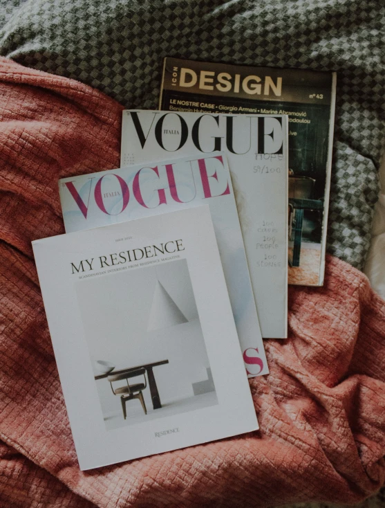 magazine covers spread out on a bed with red blanket