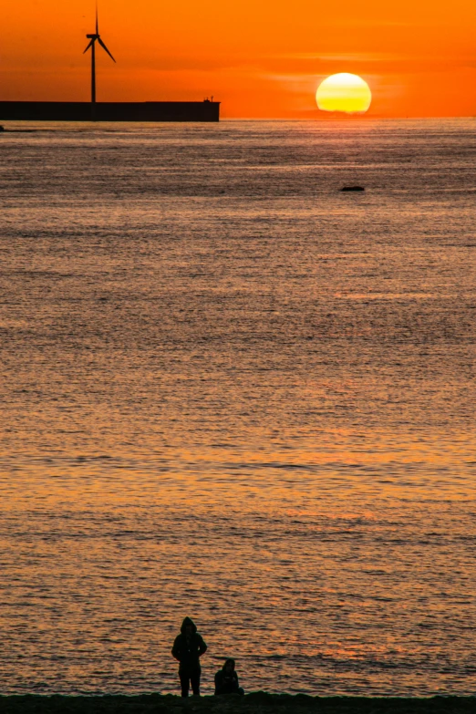 there is a person standing on a beach watching the sun set