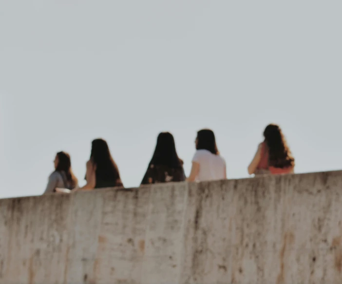 a group of people sitting on top of a cement structure