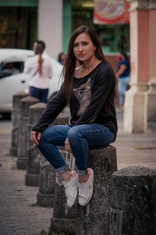 young beautiful woman sitting on cement pillar outside