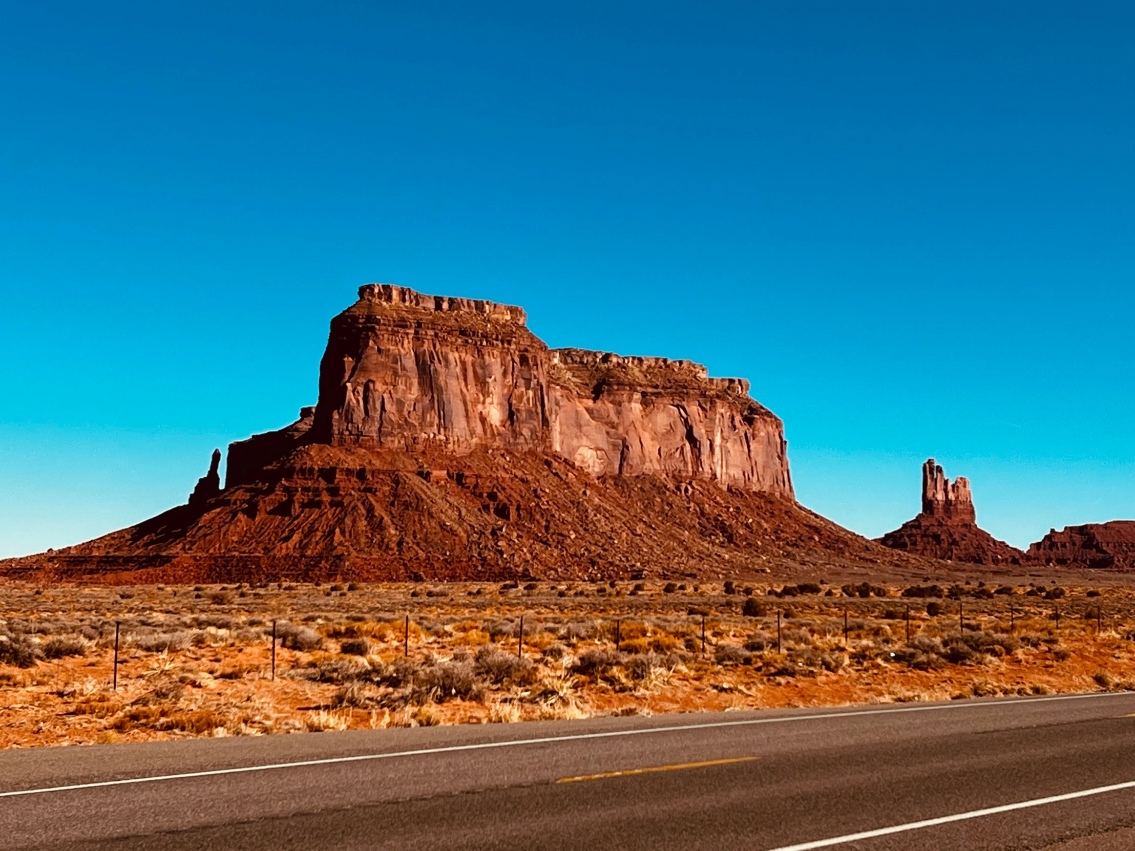 an asphalt road going past a mountain range