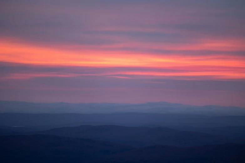 pink and blue clouds over mountains and hills