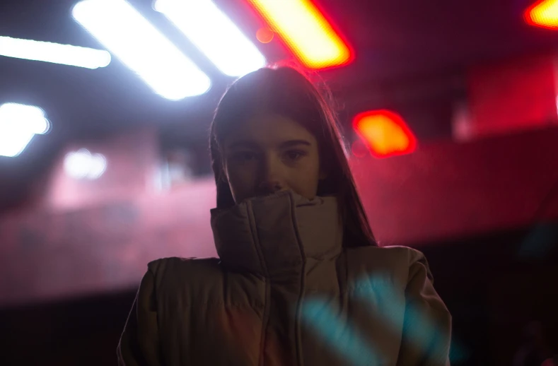 a woman wearing a jacket in the middle of a dark hallway