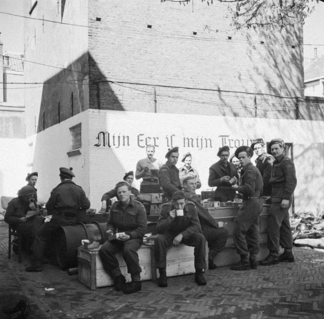 black and white pograph of men sitting on steps, in front of building