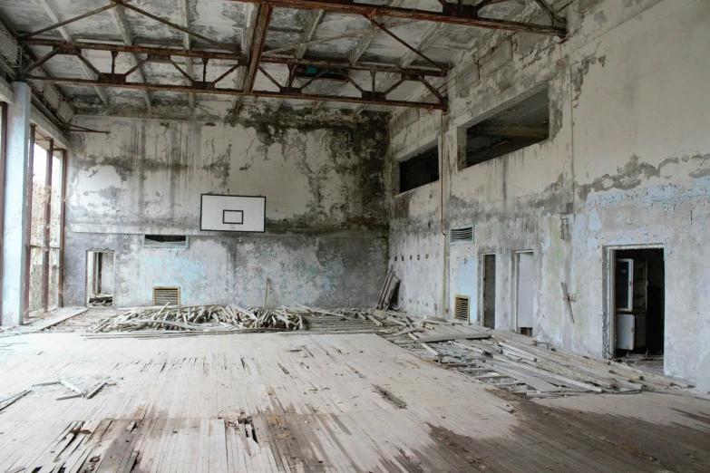 a very dirty and empty basketball court with lots of windows