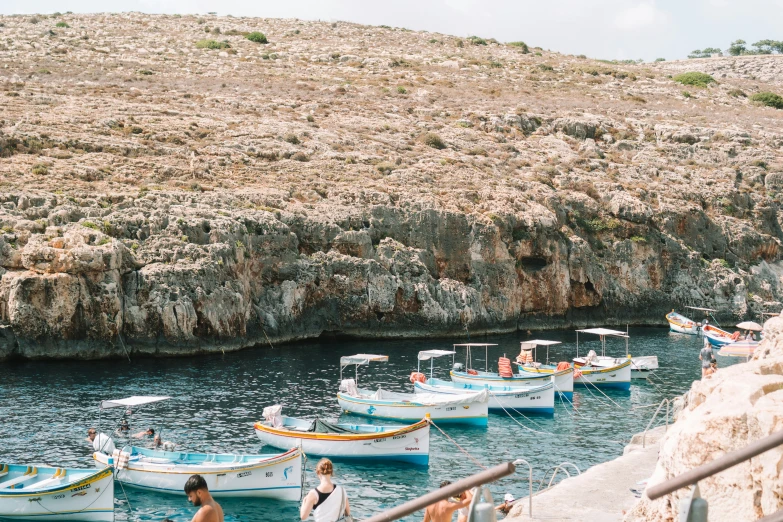 several small boats docked by the rocks and cliffs