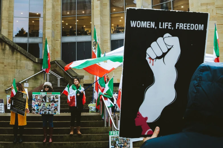 people stand in front of political posters while holding flags