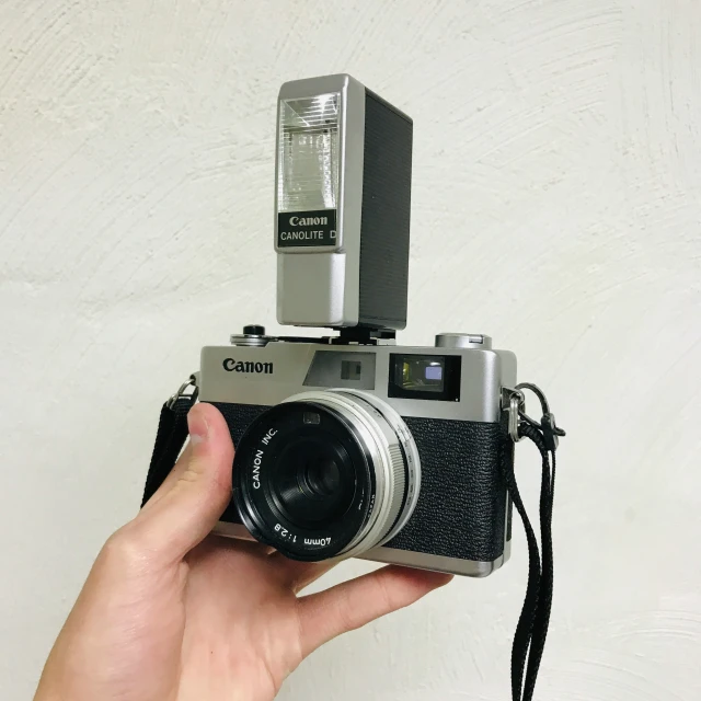 a camera being held up against the wall with a flash light on top