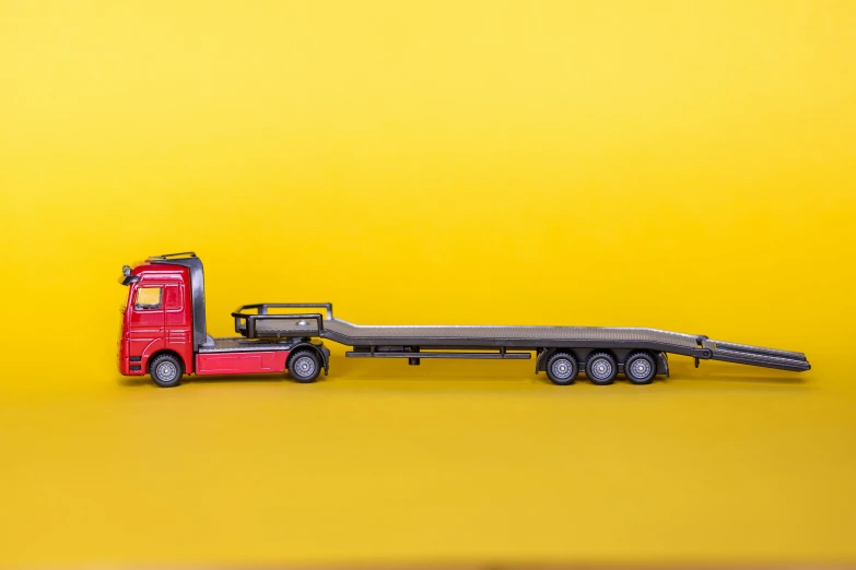 a toy red semi truck is next to the yellow backdrop