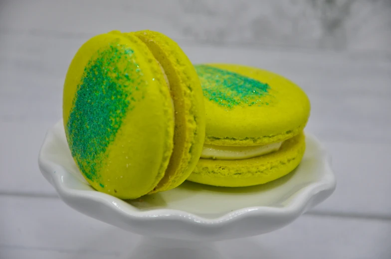 green and yellow decorated round macarons sitting on a white plate