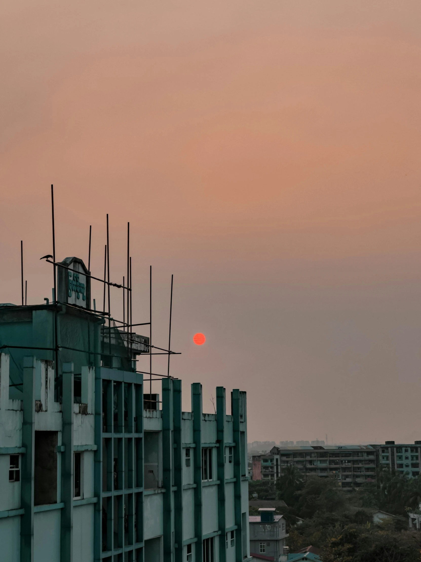 view from roof of buildings of sunset and the moon in the sky