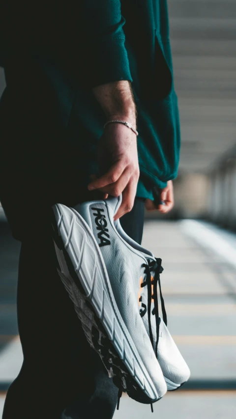 person holding shoe while walking on street next to pavement